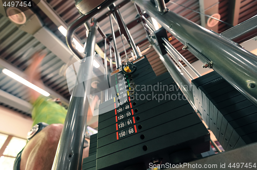 Image of Motion blurred unrecognizable person doing upper traction gym machine