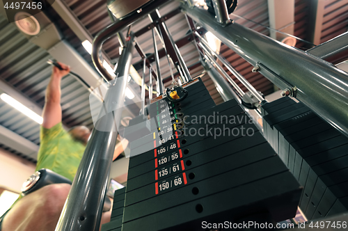 Image of Motion blurred unrecognizable person doing upper traction gym machine