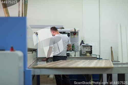 Image of worker in a factory of wooden furniture