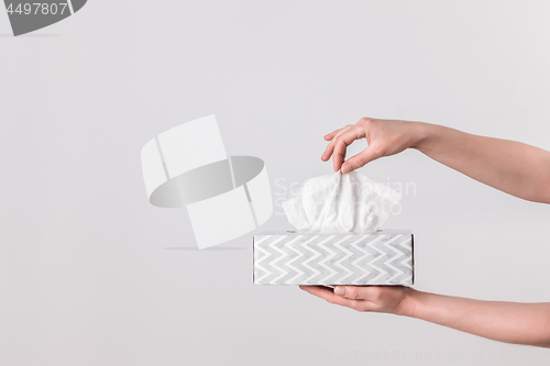 Image of Delicate female hands holding a tissue box