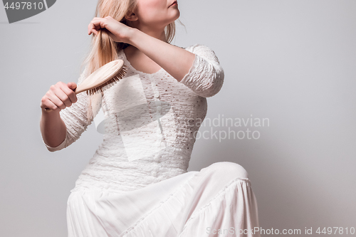 Image of Lady in white brushing her blond hair