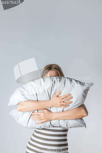 Image of Young woman hugging a gray pillow