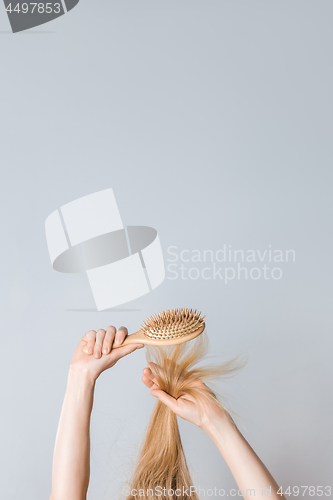 Image of Brushing blond hair with a wooden hairbrush