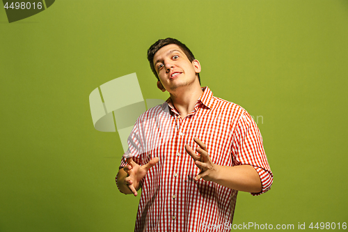 Image of The young emotional angry man screaming on green studio background