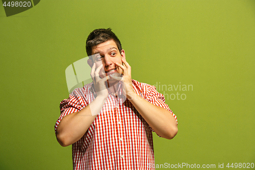 Image of Beautiful man looking suprised and bewildered isolated on green