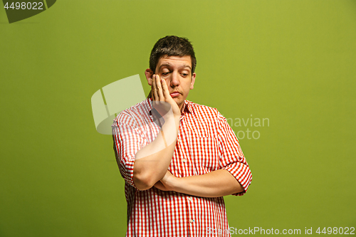 Image of Let me think. Doubtful pensive man with thoughtful expression making choice against green background