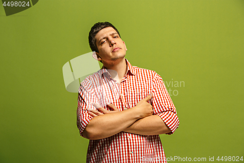 Image of Let me think. Doubtful pensive man with thoughtful expression making choice against green background