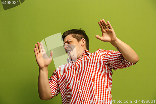 Image of Let me think. Doubtful pensive man with thoughtful expression making choice against green background