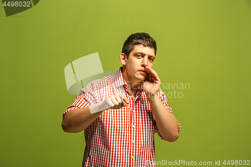 Image of The young man whispering a secret behind her hand over green background