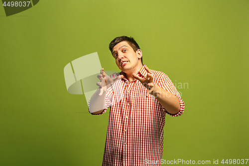 Image of The young emotional angry man screaming on green studio background