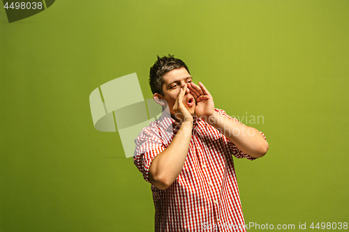 Image of Isolated on green young casual man shouting at studio