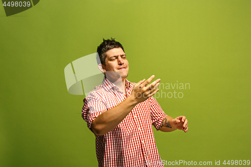 Image of Isolated on green young casual man shouting at studio