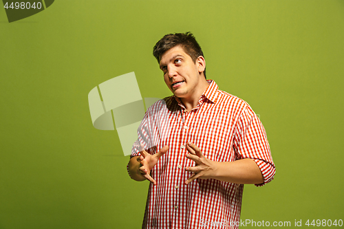 Image of The young emotional angry man screaming on green studio background