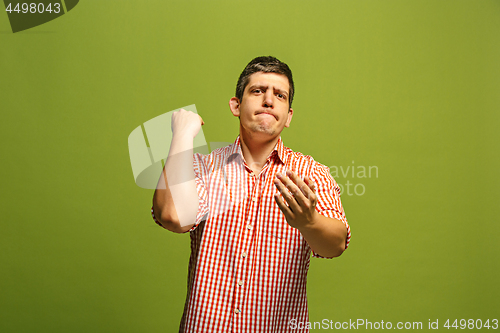 Image of Beautiful male half-length portrait isolated on green studio backgroud. The young emotional surprised man
