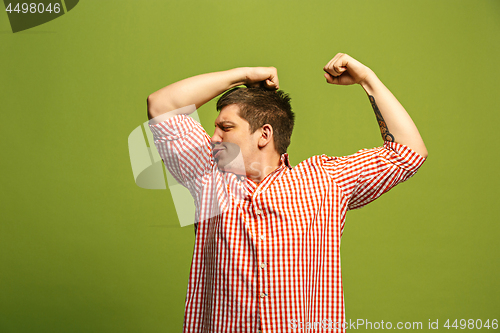 Image of Handsome young man showing biceps expressing strength and gym concept,