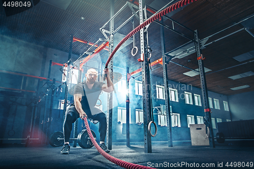 Image of Men with battle rope battle ropes exercise in the fitness gym.