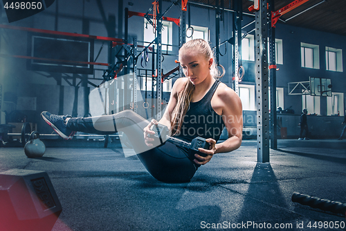 Image of Fit young woman lifting barbells working out in a gym