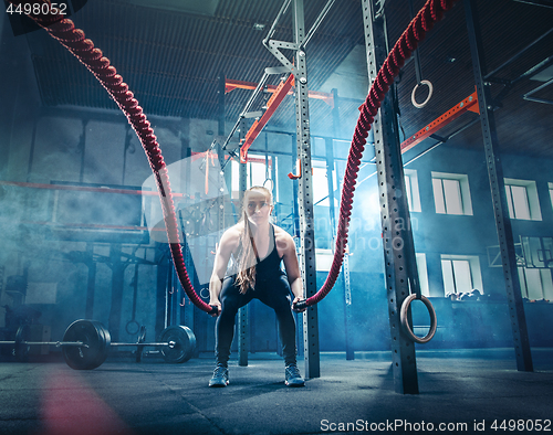 Image of Woman with battle rope battle ropes exercise in the fitness gym.