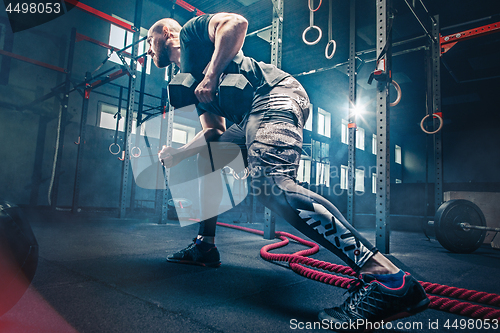 Image of Fit young man lifting barbells working out in a gym