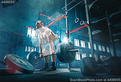 Image of Fit young man lifting barbells working out in a gym