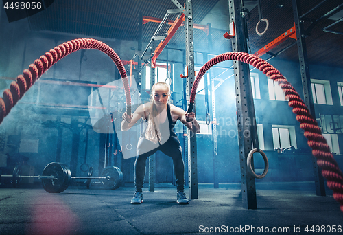 Image of Woman with battle rope battle ropes exercise in the fitness gym.