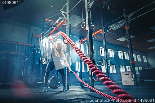 Image of Woman with battle rope battle ropes exercise in the fitness gym.