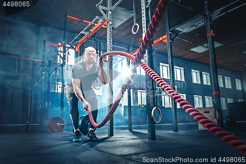 Image of Men with battle rope battle ropes exercise in the fitness gym.