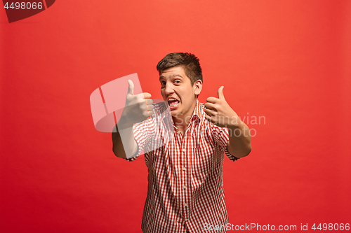 Image of The happy businessman standing and smiling against red background.