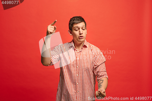 Image of Beautiful male half-length portrait isolated on red studio backgroud. The young emotional surprised man