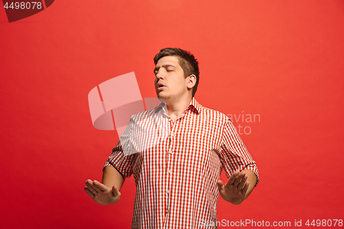 Image of Beautiful male half-length portrait isolated on red studio backgroud. The young emotional surprised man