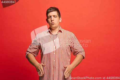 Image of Beautiful male half-length portrait isolated on red studio backgroud. The young emotional surprised man