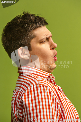 Image of The young attractive man looking suprised isolated on green