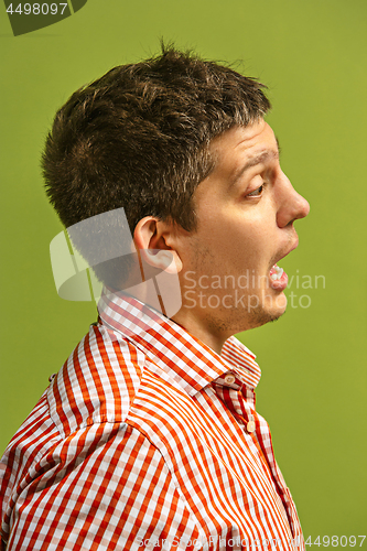 Image of The young attractive man looking suprised isolated on green