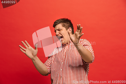 Image of Beautiful male half-length portrait isolated on red studio backgroud. The young emotional surprised man