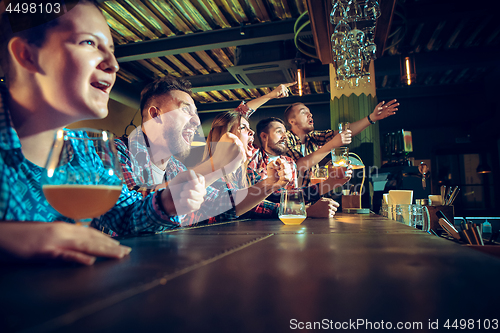 Image of Sport, people, leisure, friendship and entertainment concept - happy football fans or male friends drinking beer and celebrating victory at bar or pub