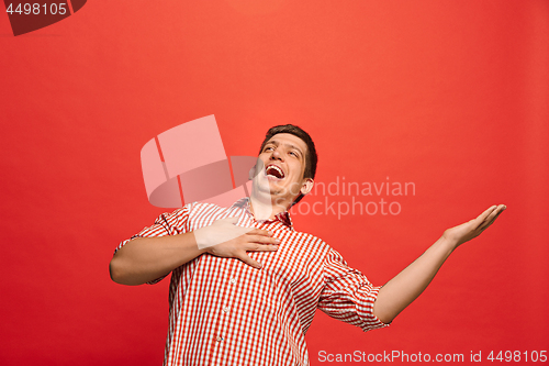 Image of The happy business man standing and smiling against red background.