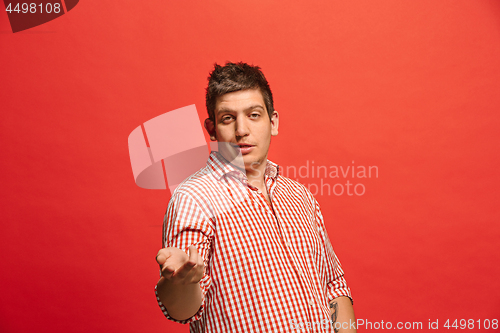 Image of Beautiful male half-length portrait isolated on red studio backgroud. The young emotional surprised man
