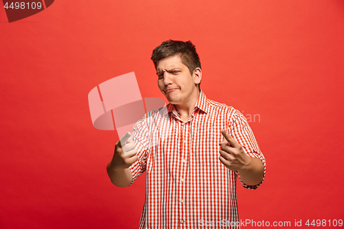 Image of The young emotional angry man screaming on red studio background