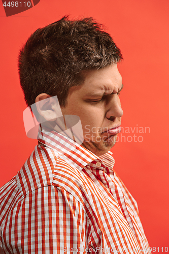 Image of Doubtful pensive man with thoughtful expression making choice against red background