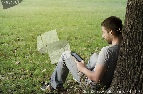 Image of 	Young man reading e-book