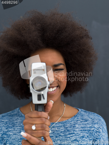 Image of african american woman using a retro video camera