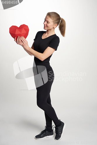 Image of Full length sport woman standing holding heart shape