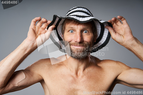 Image of Funny portrait of mature man topless wearing summer hat