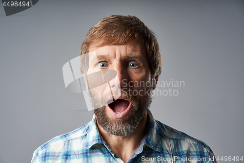 Image of Surprised mature man in checkered shirt with mouth opened