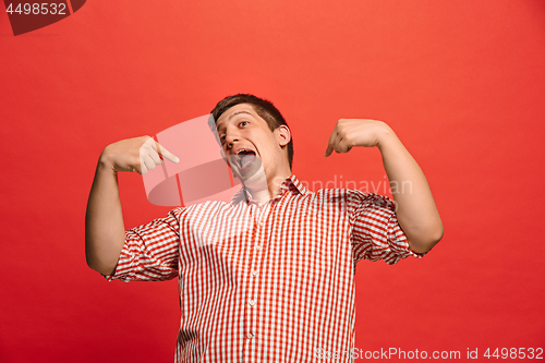 Image of The happy business man standing and smiling against red background.