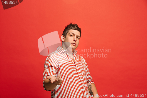 Image of Beautiful male half-length portrait isolated on red studio backgroud. The young emotional surprised man