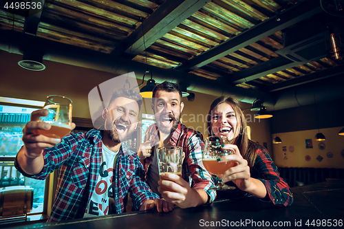 Image of Sport, people, leisure, friendship and entertainment concept - happy football fans or male friends drinking beer and celebrating victory at bar or pub