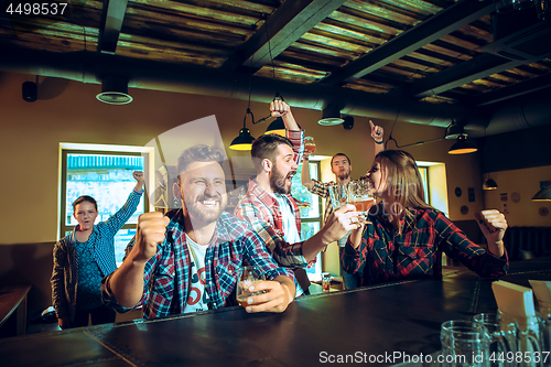 Image of Sport, people, leisure, friendship and entertainment concept - happy football fans or male friends drinking beer and celebrating victory at bar or pub