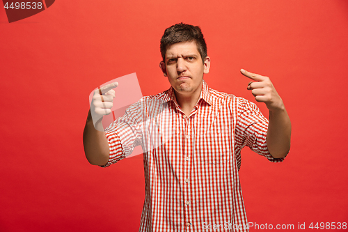 Image of The young emotional angry man screaming on red studio background