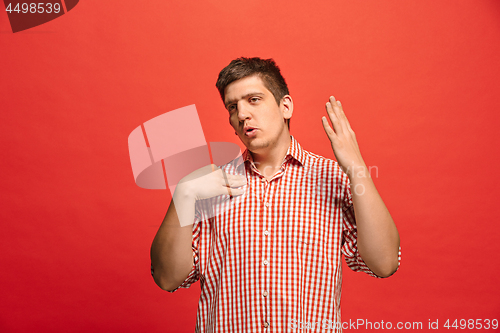 Image of Beautiful male half-length portrait isolated on red studio backgroud. The young emotional surprised man